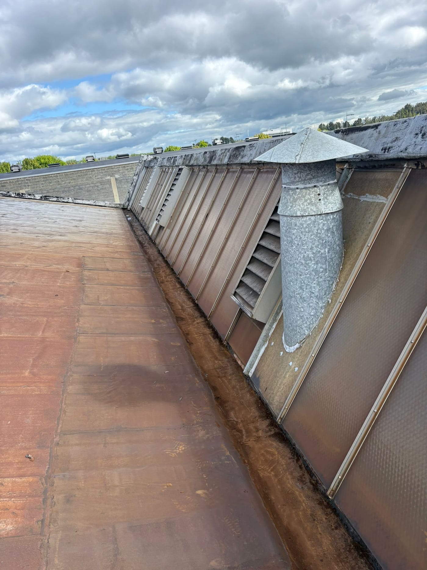 Commercial gutter cleaning along the valley of a flat industrial roof in Limerick